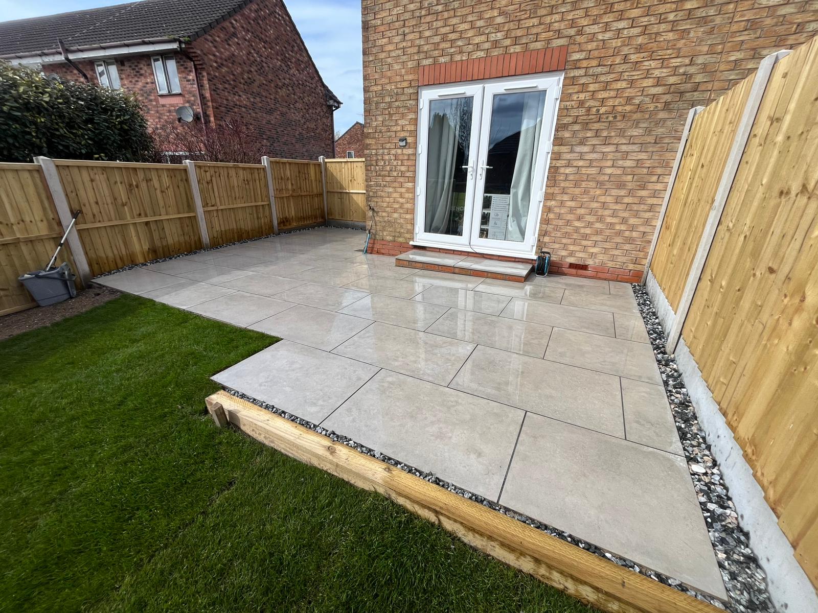 Smooth grey porcelain style patio with sleeper edging and gravel margin