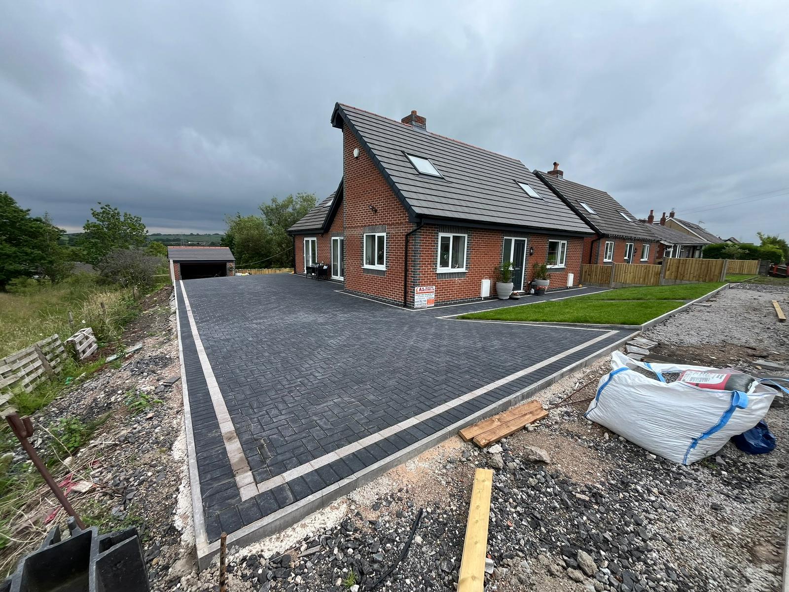 Large charcoal block paved driveway with contrasting border at a detached house